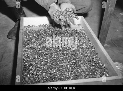 A U.S. soldier inspects thousands of gold wedding rings taken from Jews by the Germans and stashed in the Heilbronn Salt Mines, on May 3, 1945 in Germany. Stock Photo