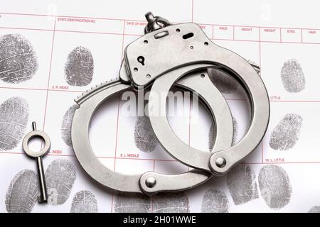 A pair of handcuffs and its key rest atop a fingerprint identification ...