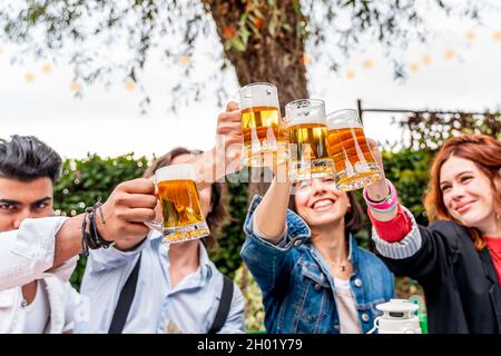 group of friends having fun at garden home party - Young people smiling together drinking beer - Focus on pints Stock Photo