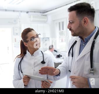 Two doctors man and woman looking at tablet and talking, in laboratory Stock Photo