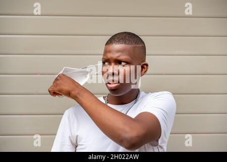 Young black man taking off the covid face mask Stock Photo