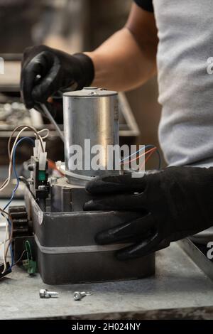 closeup to the hands of a person repairing a metal object that is on his workplace, technology and equipment restoration in workshop, professional too Stock Photo