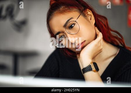 Image of beautiful asian th woman wearing glasses smiling while working with laptop in office Stock Photo