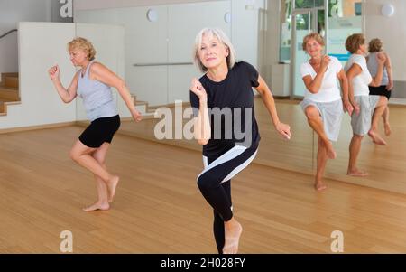 Positive aged woman practicing vigorous dance movements Stock Photo