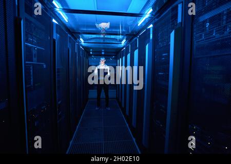Server administrator standing in hallway of data center Stock Photo