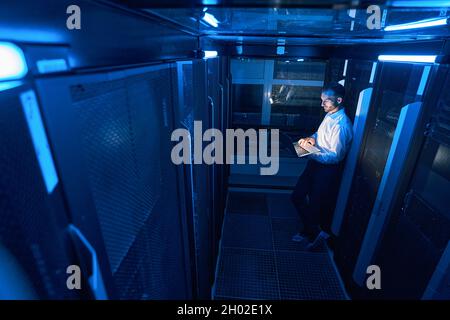 Data center operations professional programming server with laptop Stock Photo