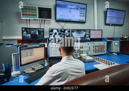 Server administrator looking after data center rooms through monitors Stock Photo