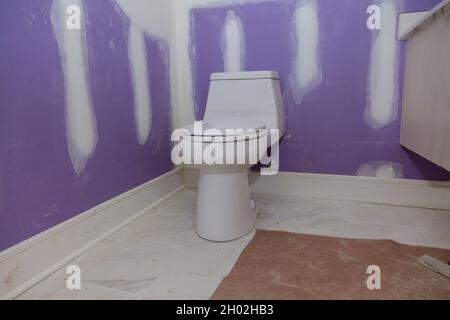 Plumber installing toilet bowl seat in restroom Stock Photo