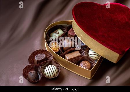 A velvet heart box holds an assortment of delicious gourmet chocolates for the one you love Stock Photo