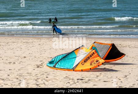 St Joseph MI USA, Sept 26, 2021; people with surf boards head into Lake Michigan, while a kite rests on the beach waiting for more wind. Stock Photo