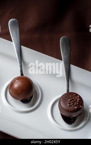 A single chocolate is placed on a tasting spoon for just a bite of gourmet chocolate Stock Photo
