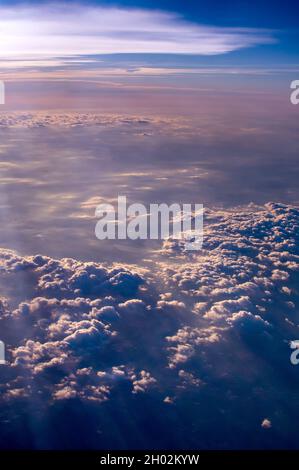 a brightly colored sunset tints layers of clouds as seen from a airplane window Stock Photo