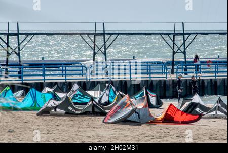 St Joseph MI USA, Sept 26, 2021; a large group of surf kites rest on the sand, as people wait for the wind to pick back up on Lake Michigan Stock Photo