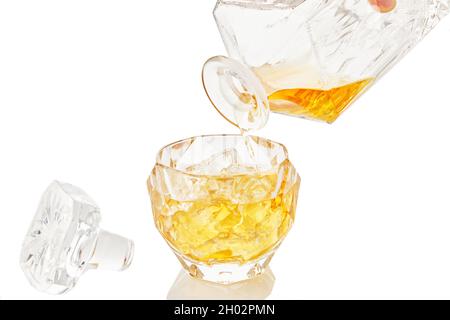Whiskey from decanter is poured into glass of whiskey with ice on white background with reflection Stock Photo