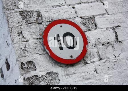 Sign displaying the number 10 on a painted brick wall. Stock Photo