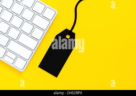 Black price tag with wireless keyboard for online shopping on yellow background. Cyber Monday and Black Monday concept. Stock Photo