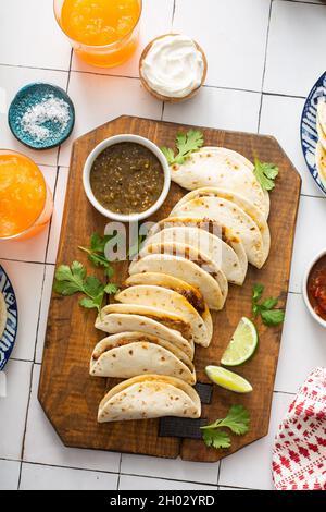 Baked tacos with pulled beef and cheese served with sour cream and salsa verde Stock Photo