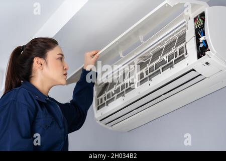 female technician service checking and repairing the air conditioner indoors Stock Photo