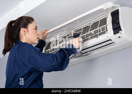 female technician service cleaning the air conditioner indoors Stock Photo