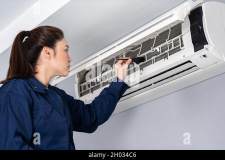 technician service using brush to cleaning the air conditioner indoors Stock Photo