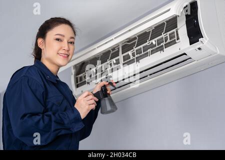 female technician service cleaning the air conditioner indoors Stock Photo