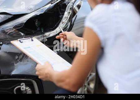 Insurance agent inspects damage to car after accident closeup Stock Photo