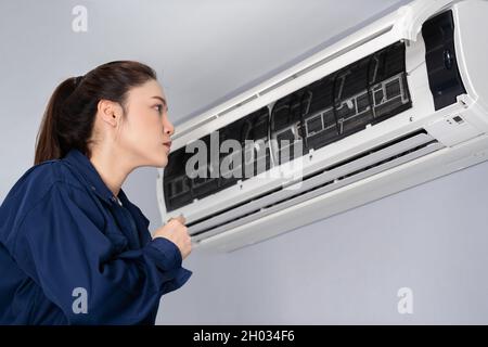 female technician service checking and repairing the air conditioner indoors Stock Photo