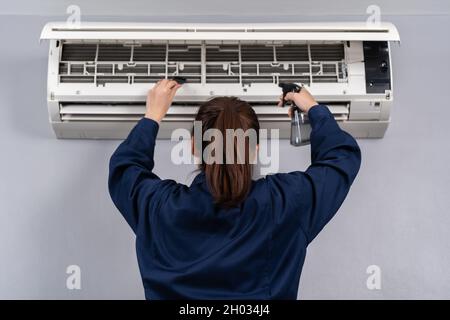 female technician service cleaning the air conditioner indoors Stock Photo