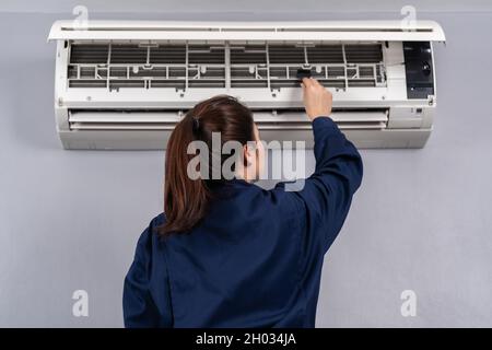 technician service using brush to cleaning the air conditioner indoors Stock Photo