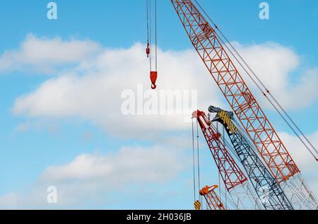 Crawler crane against blue sky and white clouds. Real estate industry. Red crawler crane use reel lift up equipment in construction site. Crane Stock Photo