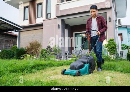 man using a lawn mower cutting grass at home Stock Photo