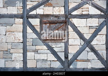 Ancient window exterior with closed wooden blinds on stone walls. Ancient Greek architecture. Stock Photo