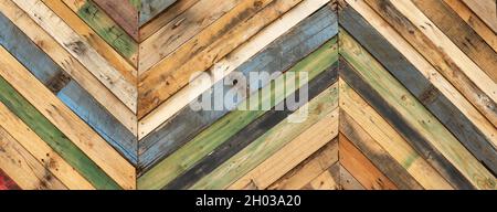 Highly unique abstract geometric patterns made from recycled cut timber palettes arranged in diagonal stripes. Multi colored textural upcycled planks Stock Photo
