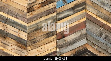Highly unique abstract geometric patterns made from recycled cut timber palettes arranged in diagonal stripes. Multi colored textural upcycled planks Stock Photo