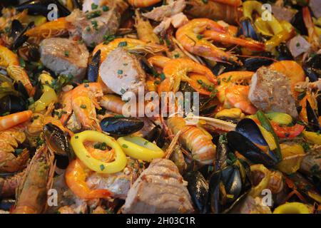 Freshly made paella, showcasing the fruits of the sea, waiting to bought to complement the many other foods available at the farmers market. Stock Photo