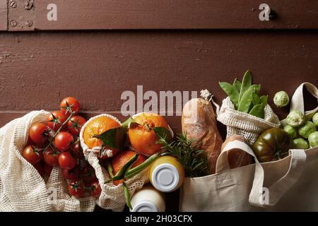 From above of fresh various groceries in eco friendly textile bags arranged on wooden table Stock Photo