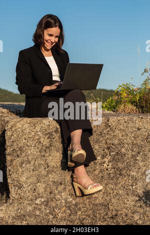 Young woman working on laptop in nature Stock Photo