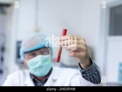Close up of doctor's hand holding test tube with blood. Epidemic testing in laboratory Stock Photo