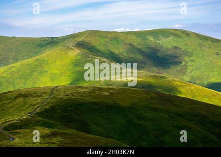 rolling hills of borzhava mountains. path through thetop of the ridge. beautiful nature scenery with grassy slopes in dappled light. wonderful summer Stock Photo