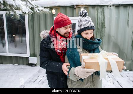Smiling man in winter clothes gifted woman with a present in a bow-tied box Stock Photo