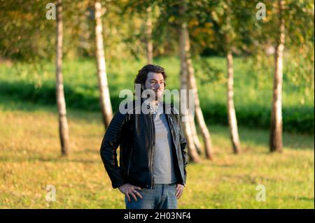 Young bearded man standing and looking at distance against a background of colorful autumn trees Stock Photo