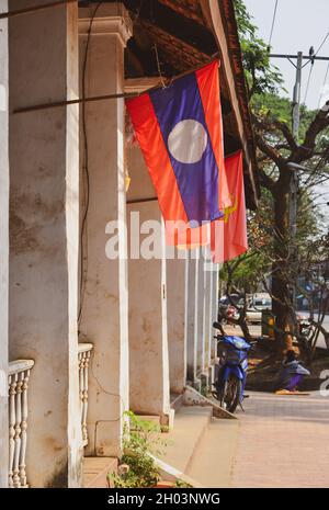 Luang Phrabang, Laos - Feb 3, 2020. The Laos national flag hanging in front of the house at old town of Luang Phrabang, Laos. Stock Photo