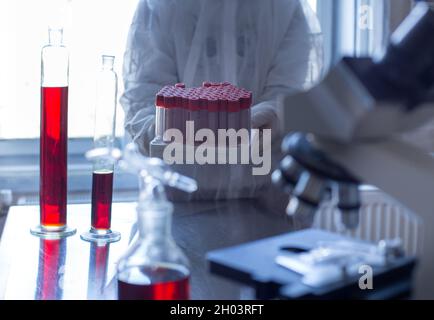 Close up of biologist's hand holding test tubes in laboratory Stock Photo