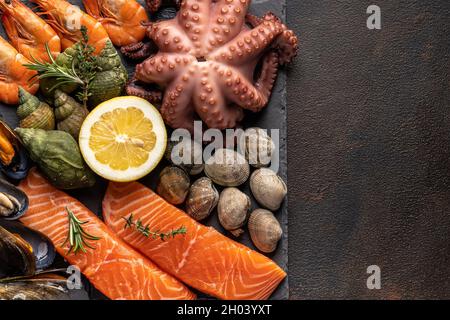 Raw fish, octopus, shrimp, snails on a stone plate. Seafood. Top view. Free space for copying. Stock Photo