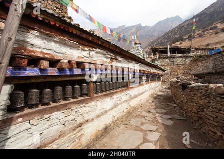 Buddhist prayer many wall with prayer wheels in nepalese village, round Annapurna circuit trekking trail, Nepal Stock Photo