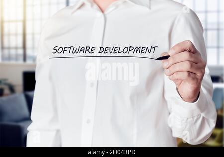 Businessman hand holds a pen and underlines the words software development on a virtual screen. Stock Photo
