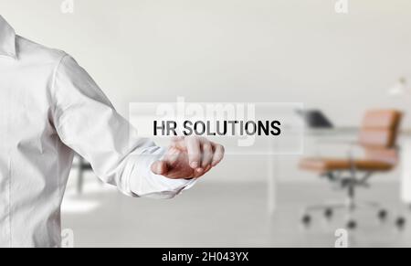 Businessman pressing the word HR solutions on a virtual search display screen. Business human resources support or service concept. Stock Photo