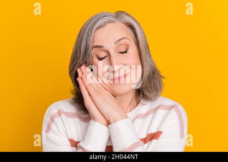 Portrait of attractive cheerful dreamy grey-haired woman resting sleeping fantasizing isolated over bright yellow color background Stock Photo