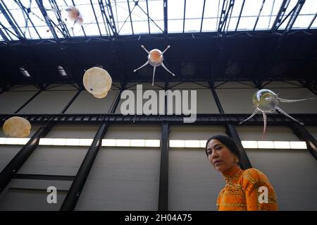 Artist Anicka Yi poses with her floating machines - called aerobes, which are filled with helium, propelled by rotors and powered by a small battery pack, and respond to different elements of their environment - during the Tate Modern press view in London, for the Hyundai Commission. Picture date: Monday October 11, 2021. Stock Photo