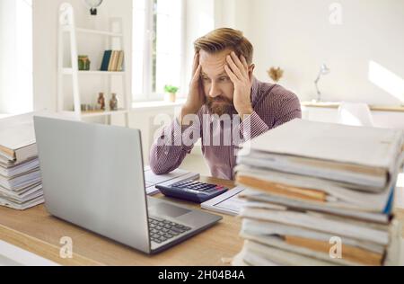 Tired exhausted male office worker working all day on financial report counting figures. Stock Photo